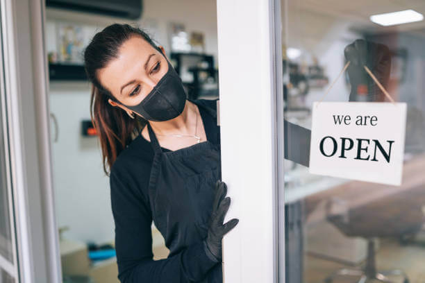 Happy Business Owner Hanging An Open Sign In Her Storefront Door In Her Salon Happy Business Owner Hanging An Open Sign In Her Storefront Door In Her Salon